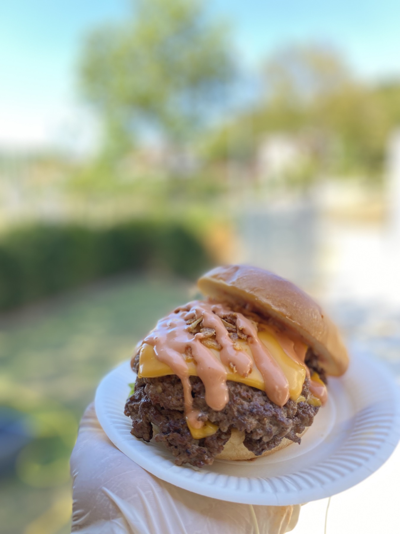 Doppelter Smash Burger auf einem Pappteller, im Freien in der Hand gehalten