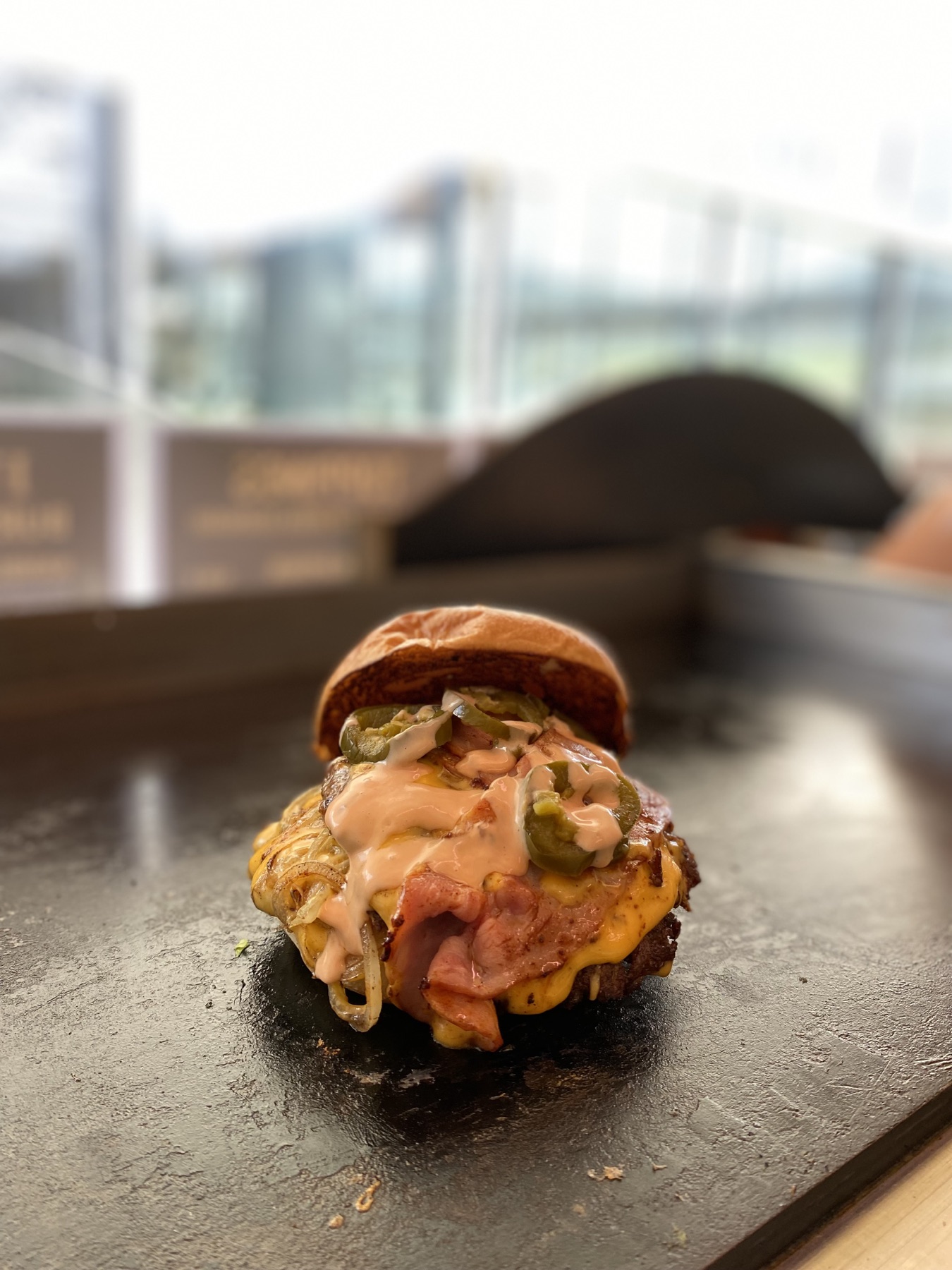 Burger mit Bacon, Käse, Jalapeños und cremiger Sauce auf der heißen Griddle